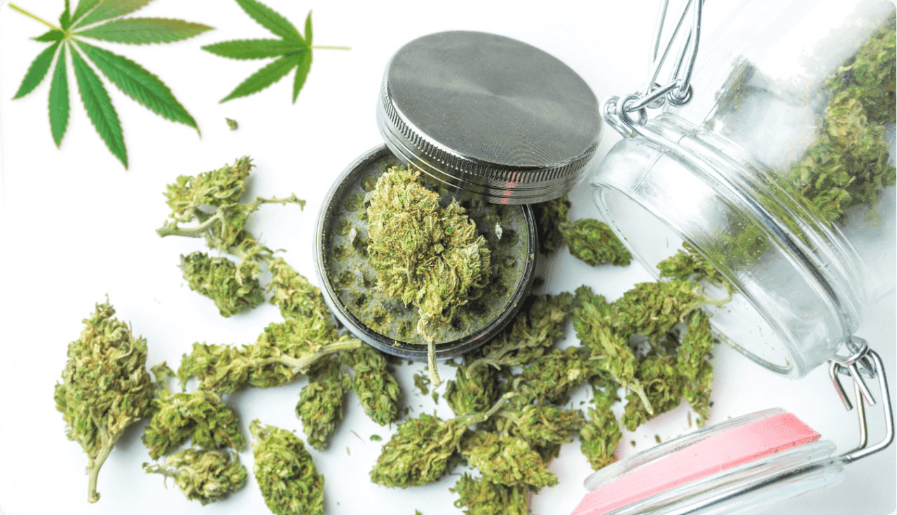 Ein Glas aus dem Cannabis-Blüten herausgeschüttet wurden und ein Grinder.